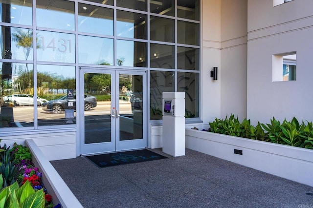 view of exterior entry featuring french doors and stucco siding