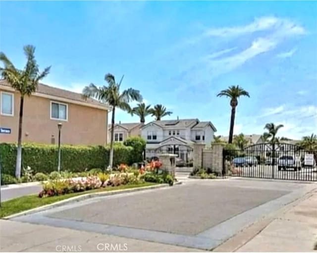 view of asphalt street featuring a gate, curbs, a residential view, and a gated entry