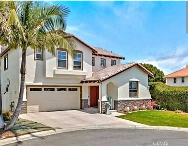 mediterranean / spanish-style home with stucco siding, concrete driveway, stone siding, a tile roof, and an attached garage
