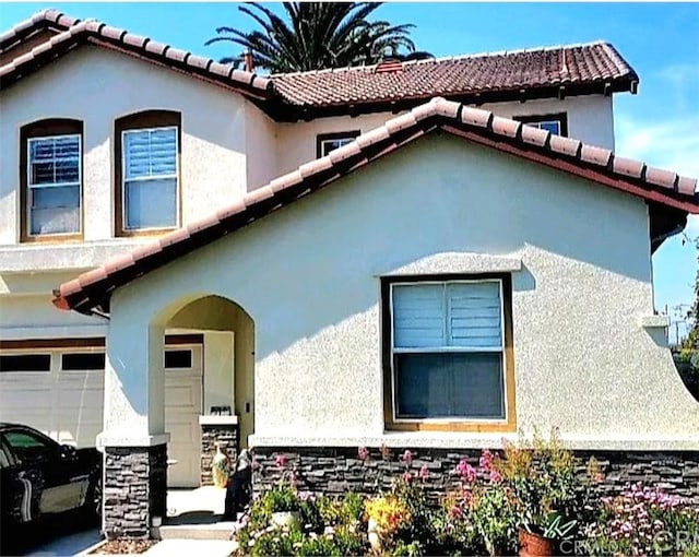 view of front of home featuring a tile roof, stucco siding, and an attached garage