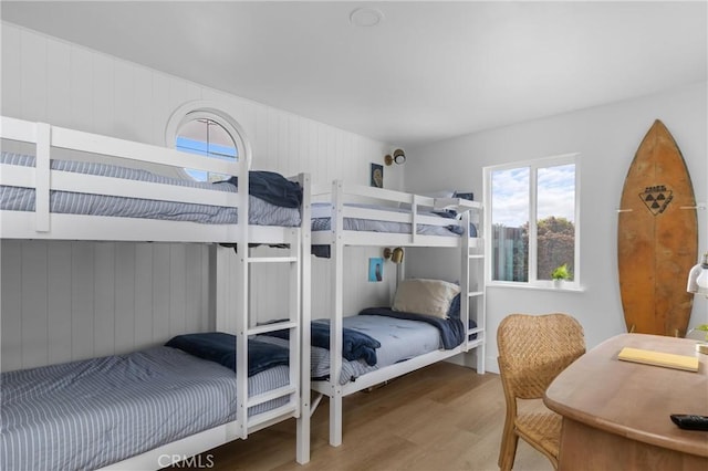 bedroom featuring wood finished floors and wooden walls