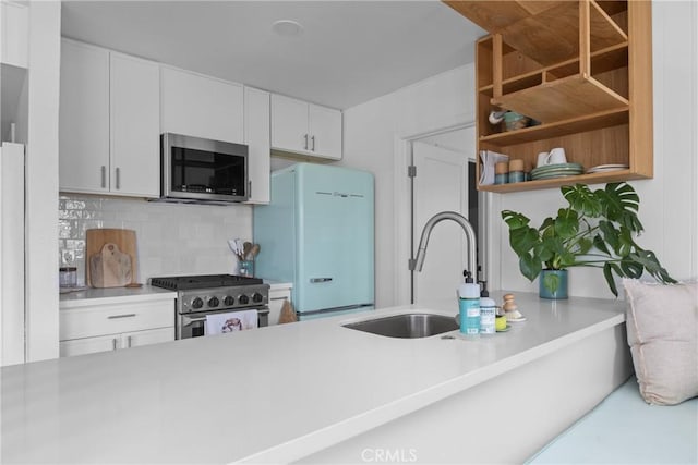 kitchen with stainless steel appliances, a sink, light countertops, tasteful backsplash, and white cabinetry