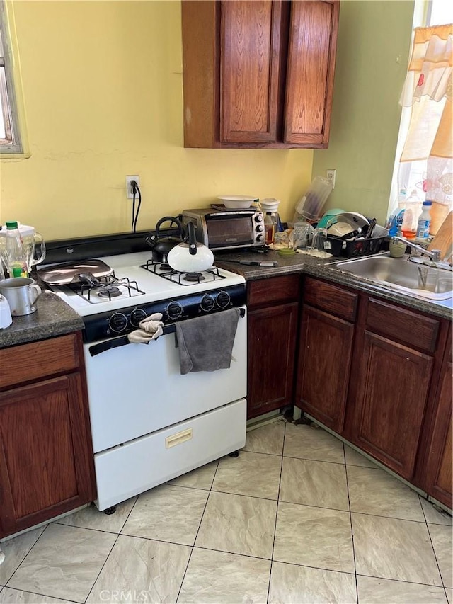kitchen featuring gas range oven, a sink, and dark countertops