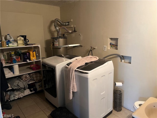 clothes washing area featuring tile patterned flooring, water heater, and washer and dryer