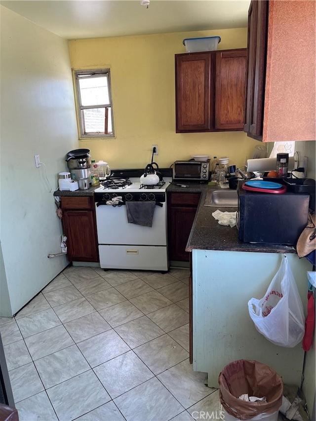 kitchen featuring white gas stove and dark countertops
