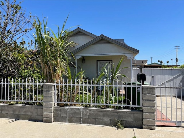 view of front facade featuring a fenced front yard, stucco siding, and a gate