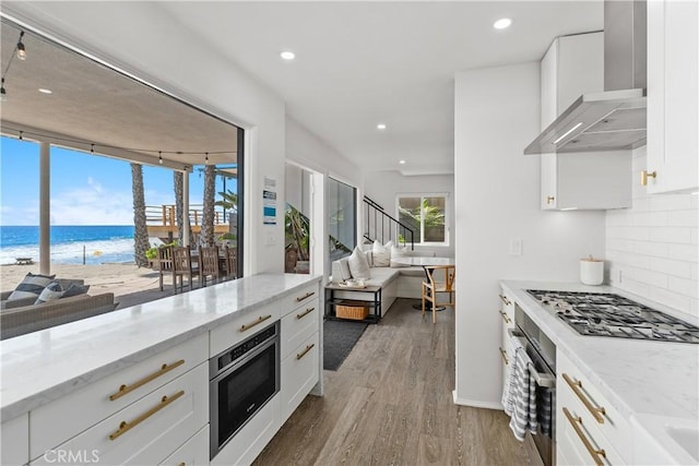 35581 Beach Rd, Dana Point, CA 92624 - kitchen with wall chimney range hood, stainless steel appliances, wood finished floors, view of water and beach, and open floor plan