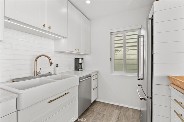 35581 Beach Rd, Dana Point, CA 92624 - kitchen with stainless steel dishwasher, light wood finished floors, decorative backsplash, white cabinets, and light countertops