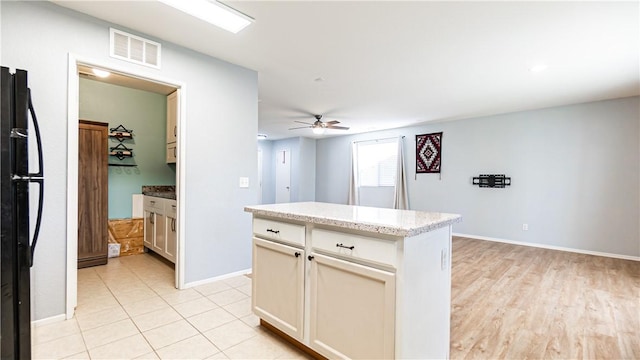 3261 James Ct, Lancaster, CA 93535 - kitchen with ceiling fan, freestanding refrigerator, baseboards, a kitchen island, and light stone counters