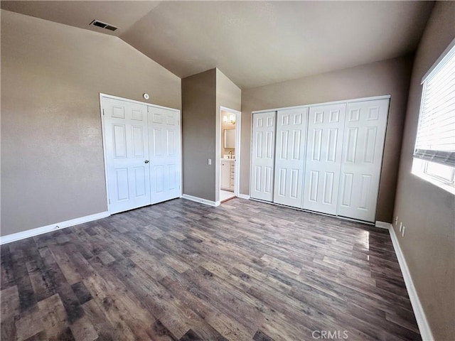unfurnished bedroom with dark wood-type flooring, vaulted ceiling, and baseboards