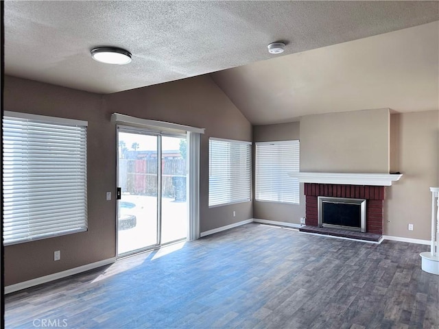 unfurnished living room with wood finished floors, baseboards, a textured ceiling, vaulted ceiling, and a fireplace