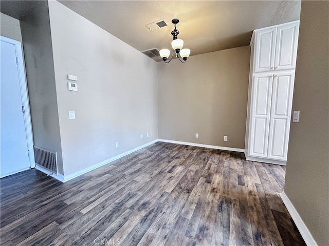 unfurnished dining area with dark wood-type flooring, a chandelier, and baseboards
