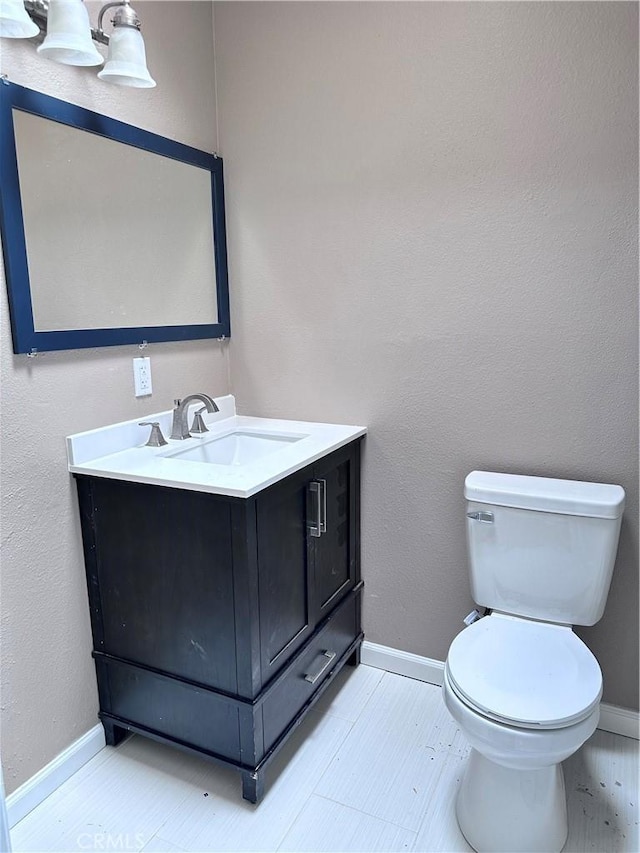 bathroom featuring toilet, vanity, and baseboards