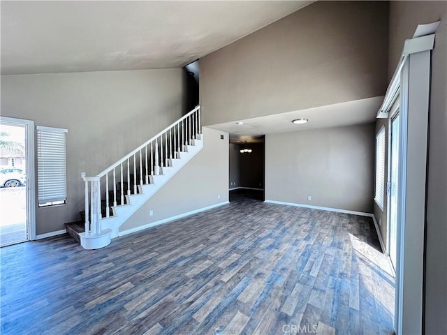 unfurnished living room with stairway, high vaulted ceiling, wood finished floors, and baseboards