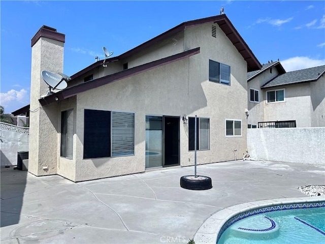 rear view of property with a patio, fence, stucco siding, and a chimney