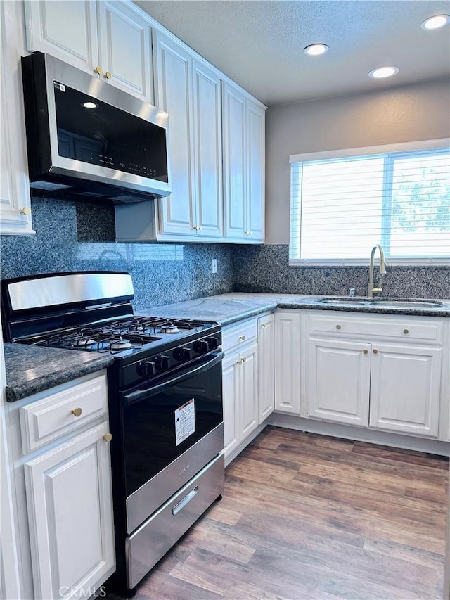 kitchen with appliances with stainless steel finishes, a sink, white cabinetry, recessed lighting, and a textured ceiling
