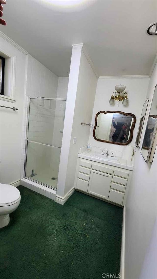 bathroom with a stall shower, toilet, baseboards, vanity, and crown molding