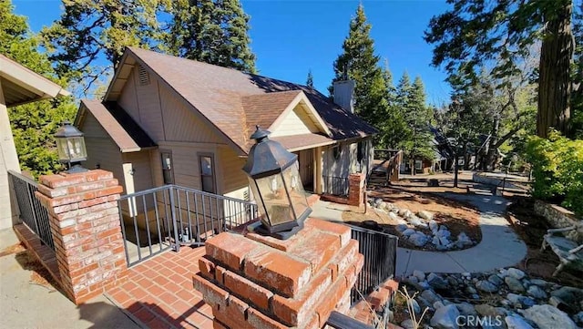 view of front of house with roof with shingles and a chimney