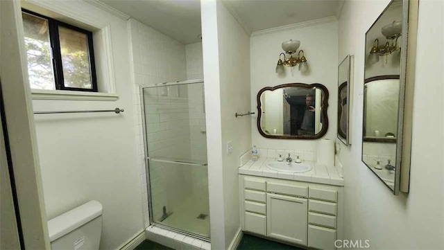 bathroom featuring toilet, a stall shower, vanity, and crown molding