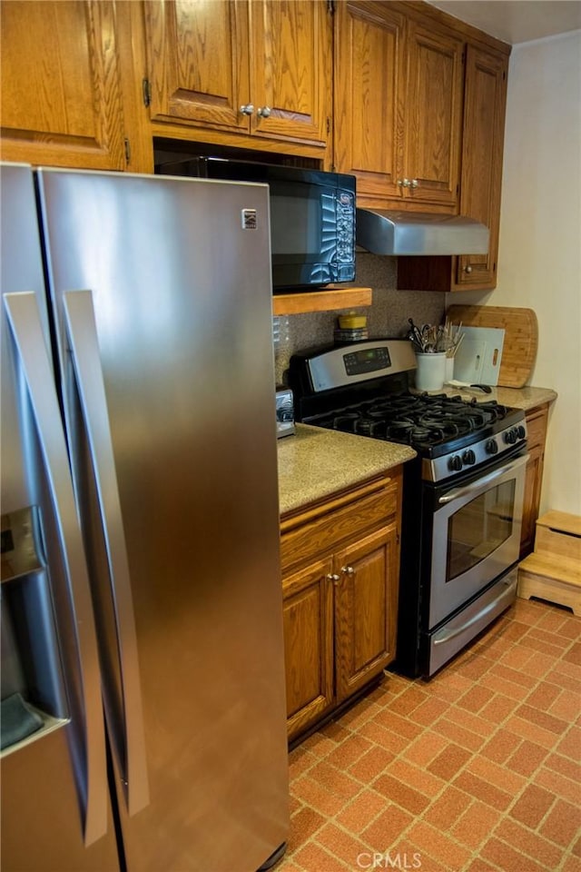 2619 Mary St, La Crescenta, CA 91214 - kitchen featuring stainless steel appliances, brown cabinets, under cabinet range hood, brick patterned floors, and light countertops