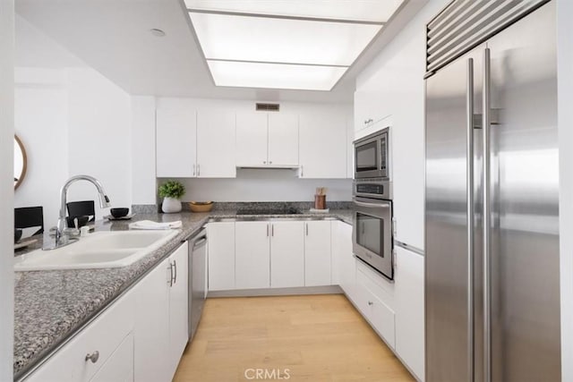 850 E Ocean Blvd Unit 602, Long Beach, CA 90802 - kitchen with stainless steel appliances, white cabinets, light wood-style floors, and stone countertops
