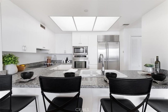 850 E Ocean Blvd Unit 602, Long Beach, CA 90802 - kitchen featuring built in appliances, under cabinet range hood, a kitchen bar, a peninsula, and white cabinets