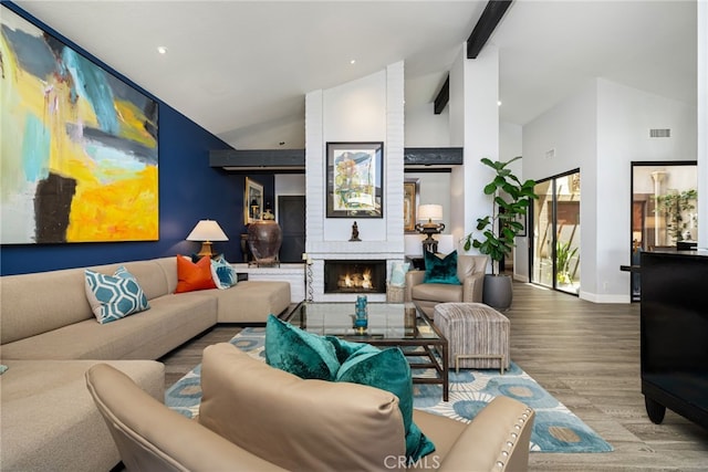 living area featuring wood finished floors, high vaulted ceiling, baseboards, beam ceiling, and a brick fireplace