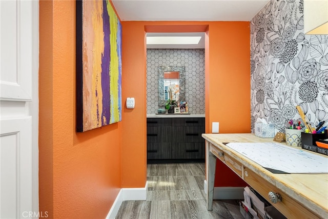 bathroom with baseboards, vanity, and an accent wall