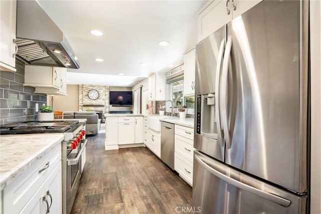 17301 Elsinore Cir, Huntington Beach, CA 92647 - kitchen with stainless steel appliances, wall chimney exhaust hood, open floor plan, a sink, and dark wood-style flooring