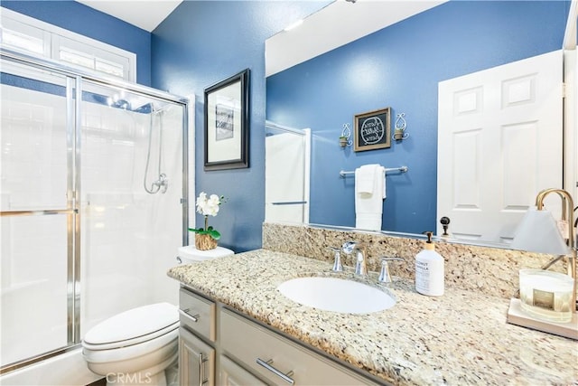 full bathroom with a stall shower, toilet, and vanity