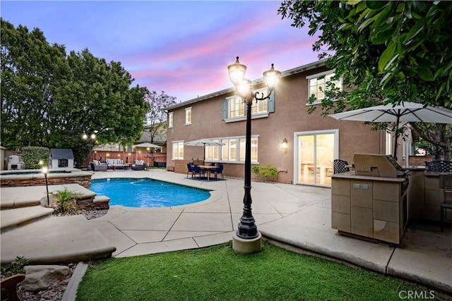 view of swimming pool with exterior kitchen, fence, a patio, and a pool with connected hot tub
