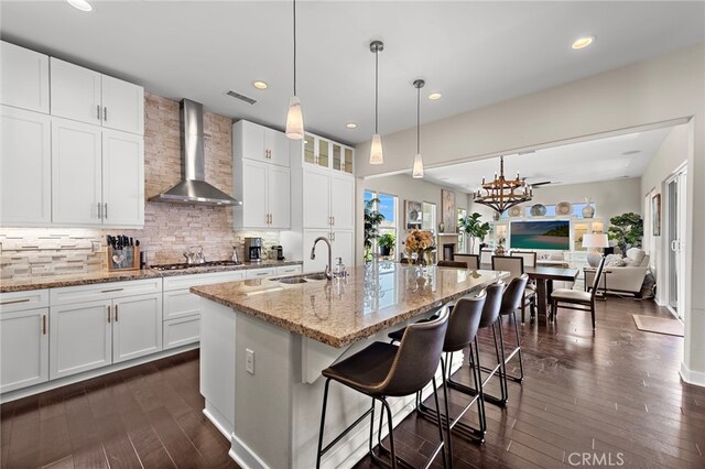 7051 Sitio Caliente, Carlsbad, CA 92009 - kitchen featuring wall chimney range hood, a sink, stainless steel gas cooktop, decorative backsplash, and dark wood finished floors