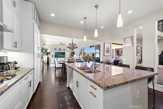 7051 Sitio Caliente, Carlsbad, CA 92009 - kitchen featuring open floor plan, a sink, a kitchen bar, dark wood-style flooring, and light stone counters