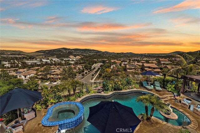 7051 Sitio Caliente, Carlsbad, CA 92009 - pool at dusk featuring an in-ground hot tub, a mountain view, an outdoor pool, and a patio