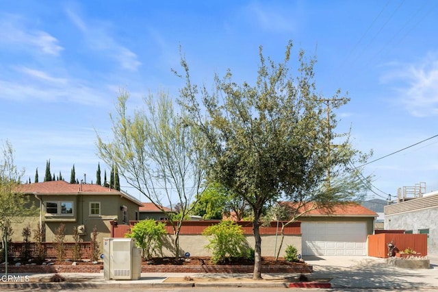 view of front of home with fence, stucco siding, and driveway
