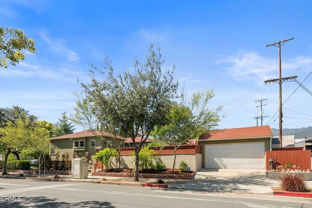 view of front facade featuring fence, an attached garage, stucco siding, and concrete driveway