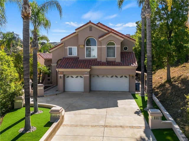 mediterranean / spanish-style home with stucco siding, a garage, driveway, and a tile roof