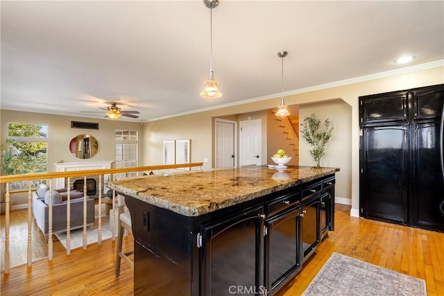 10885 San Marcos Rd, Atascadero, CA 93422 - kitchen with dark cabinetry, a center island, a ceiling fan, light wood-style floors, and ornamental molding