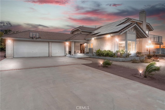 36755 Tierra Subida Ave, Palmdale, CA 93551 - view of front of house with an attached garage, concrete driveway, a chimney, solar panels, and stucco siding