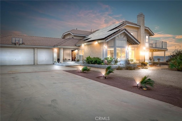 36755 Tierra Subida Ave, Palmdale, CA 93551 - view of front of home featuring a balcony, solar panels, an attached garage, a chimney, and driveway