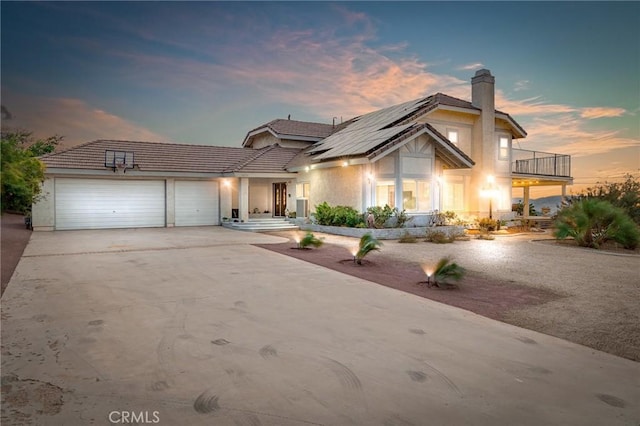 36755 Tierra Subida Ave, Palmdale, CA 93551 - view of front of house with a balcony, a chimney, an attached garage, roof mounted solar panels, and concrete driveway