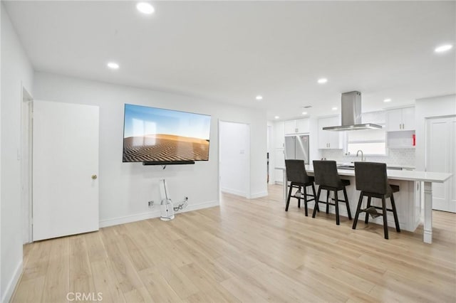 3686 Palo Verde Ave, Long Beach, CA 90808 - kitchen featuring extractor fan, white cabinets, light wood-style floors, a breakfast bar, and light countertops