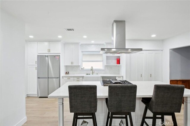3686 Palo Verde Ave, Long Beach, CA 90808 - kitchen featuring appliances with stainless steel finishes, island range hood, backsplash, a sink, and light countertops