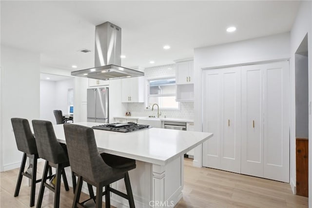 3686 Palo Verde Ave, Long Beach, CA 90808 - kitchen featuring island exhaust hood, appliances with stainless steel finishes, white cabinets, a sink, and tasteful backsplash
