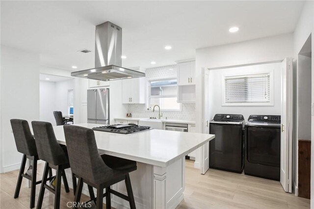 3686 Palo Verde Ave, Long Beach, CA 90808 - kitchen with island exhaust hood, appliances with stainless steel finishes, a sink, white cabinets, and washer and clothes dryer