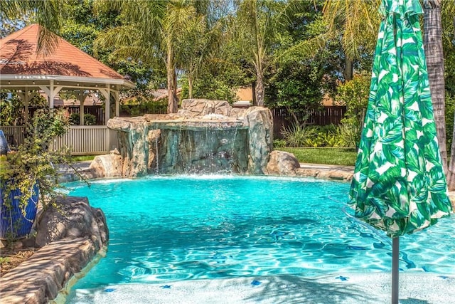 swimming pool featuring a gazebo and fence
