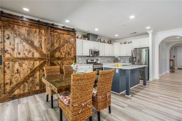 dining area featuring arched walkways, crown molding, recessed lighting, light wood finished floors, and baseboards