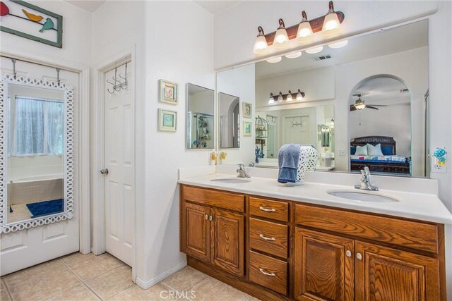 ensuite bathroom with tile patterned flooring, a ceiling fan, and double vanity