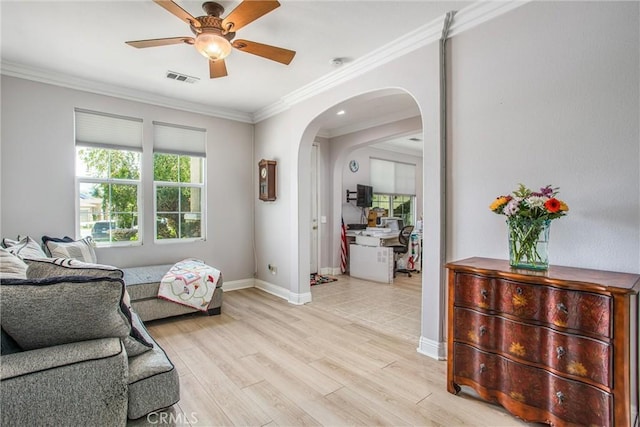 living area featuring ceiling fan, arched walkways, crown molding, baseboards, and light wood-type flooring
