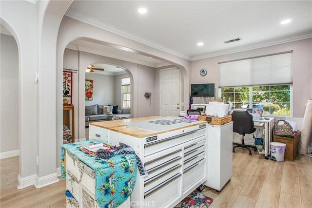 kitchen with arched walkways, open floor plan, light wood-style floors, ornamental molding, and plenty of natural light